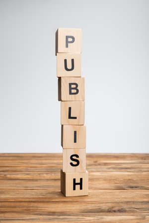 stack of cubes with publish lettering on wooden surface isolated on grayの写真素材