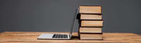 stack of books and laptop on wooden desk isolated on grey, bannerの写真素材