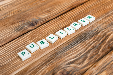white blocks with publisher lettering and numbers on wooden deskの写真素材