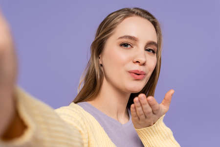young woman sending air kiss isolated on purple