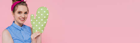 happy young woman with green baking glove isolated on pink, banner