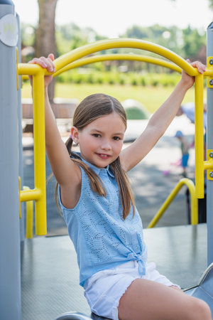 smiling girl looking at camera while having fun on playgroundの写真素材