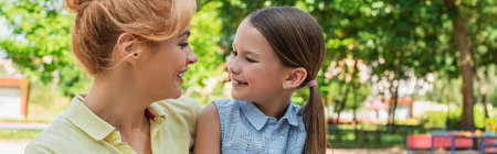 joyful daughter and mother looking at each other in park, banner