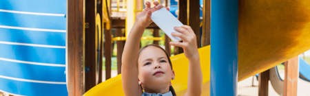 girl taking selfie on mobile phone in amusement park, bannerの写真素材