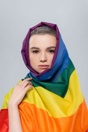 young woman with lgbt flag on head looking at camera isolated on grey