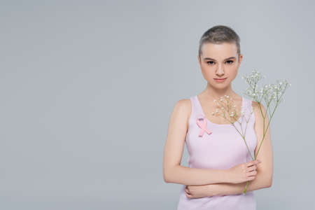 young woman with breast cancer awareness ribbon and gypsophila flowers isolated on greyの写真素材