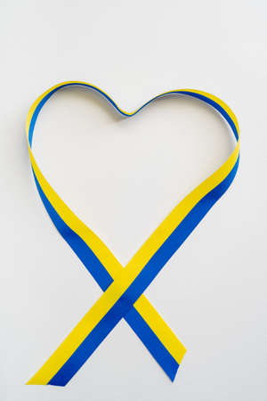 Top view of heart sign from blue and yellow ribbon on white backgroundの写真素材