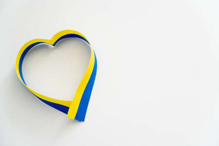 Top view of blue and yellow ribbon in heart shape on white backgroundの写真素材