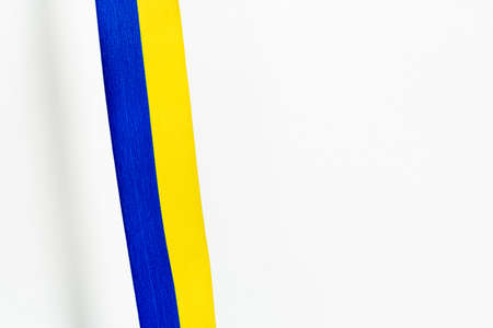 Top view of blue and yellow ribbon with shadow on white background