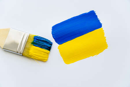 Top view of paintbrush near painted ukrainian flag on white backgroundの写真素材