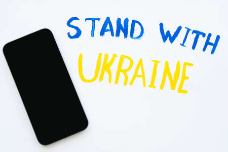 Top view of smartphone near painted stand with ukraine lettering on white background