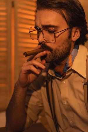 portrait of man with mustache and eyeglasses smoking cigarの写真素材