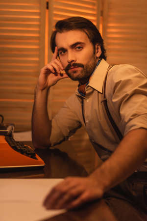 man with mustache near retro typewriter machine on desk