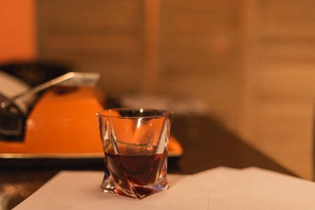 glass of whiskey near typewriter machine on deskの写真素材