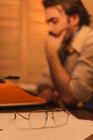 eyeglasses near blurred writer on background