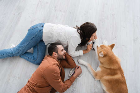 top view of happy young couple lying of floor with akita inu dogの写真素材