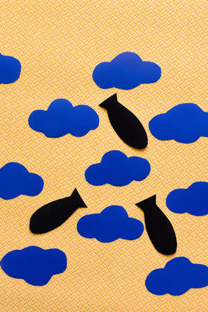 Top view of paper bombs near carton clouds on textured yellow background, war in ukraine concept