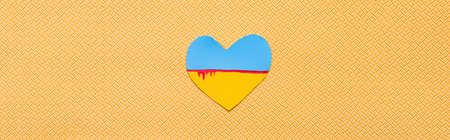 Top view of ukrainian flag with blood in heart shape on textured yellow background, bannerの写真素材