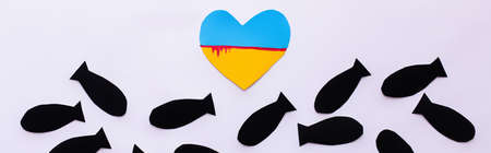 Top view of ukrainian flag in heart shape near paper bombs on white background, bannerの写真素材