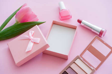 blooming tulip near decorative cosmetics and gift box on pinkの写真素材