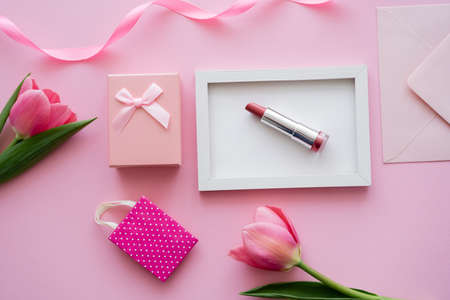 top view of tulips near frame with lipstick, envelope and gift box on pinkの写真素材