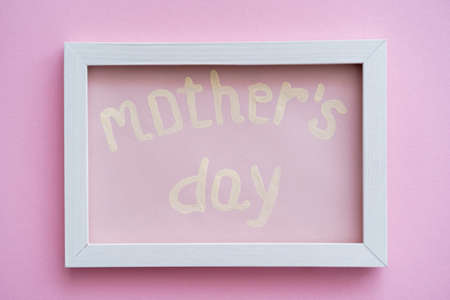 top view of greeting card with mothers day lettering in white frame on pinkの写真素材