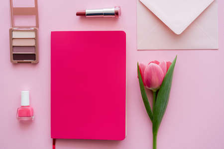 top view of tulip near notebook, envelope and decorative cosmetics on pinkの写真素材