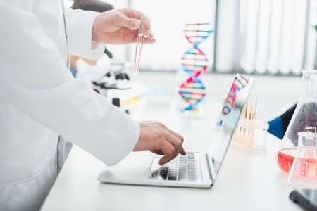 cropped view of geneticist with test tube using laptop in laboratoryの写真素材