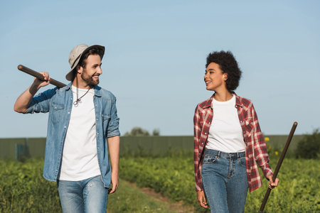 young interracial farmers smiling at each other in green fieldの写真素材