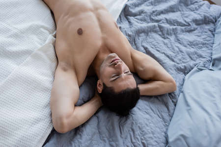 top view of shirtless man lying on bed at home