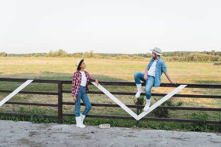 full length view of african american woman looking at farmer sitting on wooden fenceの写真素材