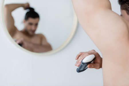 blurred man applying deodorant in bathroomの写真素材