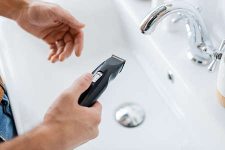 cropped view of man holding electric razor in bathroomの写真素材