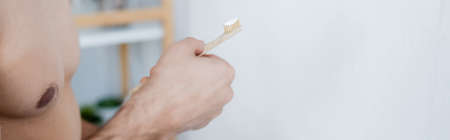 partial view of man holding toothbrush with toothpaste in bathroom, bannerの写真素材