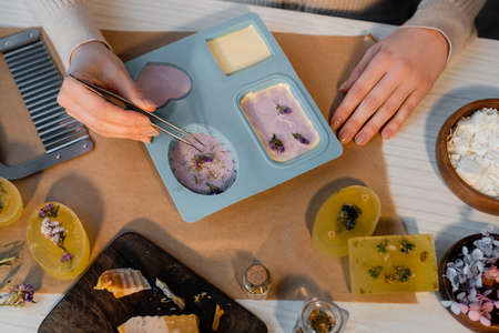 Top view of craftswoman pouring decor on craft soap in silicone mold on tableの写真素材