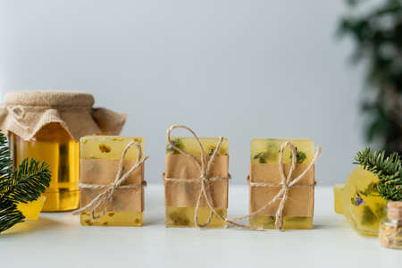 Handmade soap with twine near pine branches and blurred honey on tableの写真素材