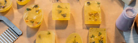 Top view of handmade soap on craft paper near cutter on table, banner