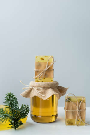 Handmade soap on jar with honey near spruce branch on grey backgroundの写真素材