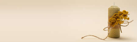 Handmade candle with dry flower on beige background, banner