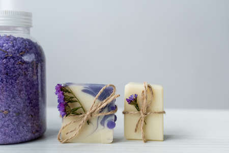 Close up view of sea salt near handmade soap with flowers on grey backgroundの写真素材