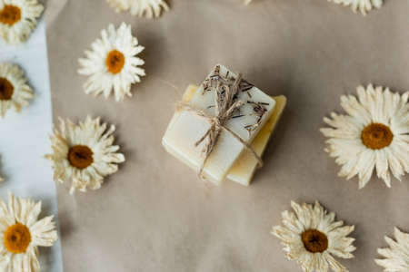 Top view of handmade soap with twine near chamomiles on craft paperの写真素材