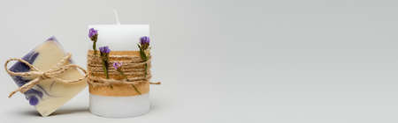 Craft candle with flowers near soap bar on grey background, bannerの写真素材