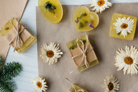 Top view of handmade soap near dry chamomiles on craft paper on tableの写真素材