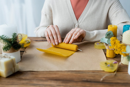 Cropped view of craftswoman making candle on craft paper at homeの写真素材