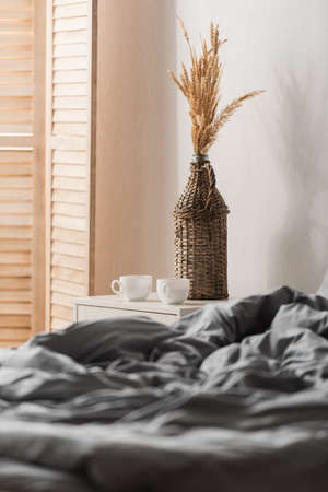 Cups of coffee on bedside table near bed at home
