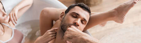 Young man with closed eyes taking bath with girlfriend at home, bannerの写真素材