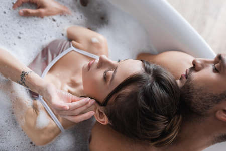 Overhead view of sexy man taking bath with young girlfriend at home