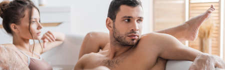 Young man taking bath with blurred girlfriend at home, bannerの写真素材