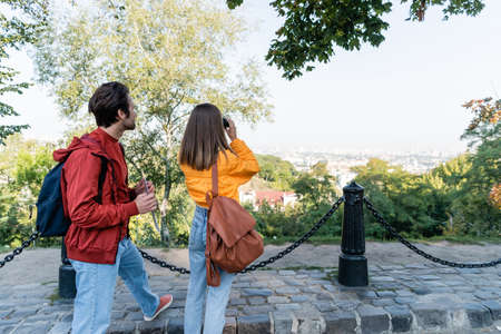 Tourist holding map near girlfriend with backpack and binoculars on urban streetの写真素材