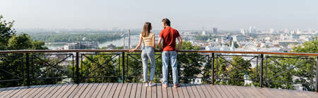 Side view of positive travelers standing near railing on viewpoint in city, bannerの写真素材
